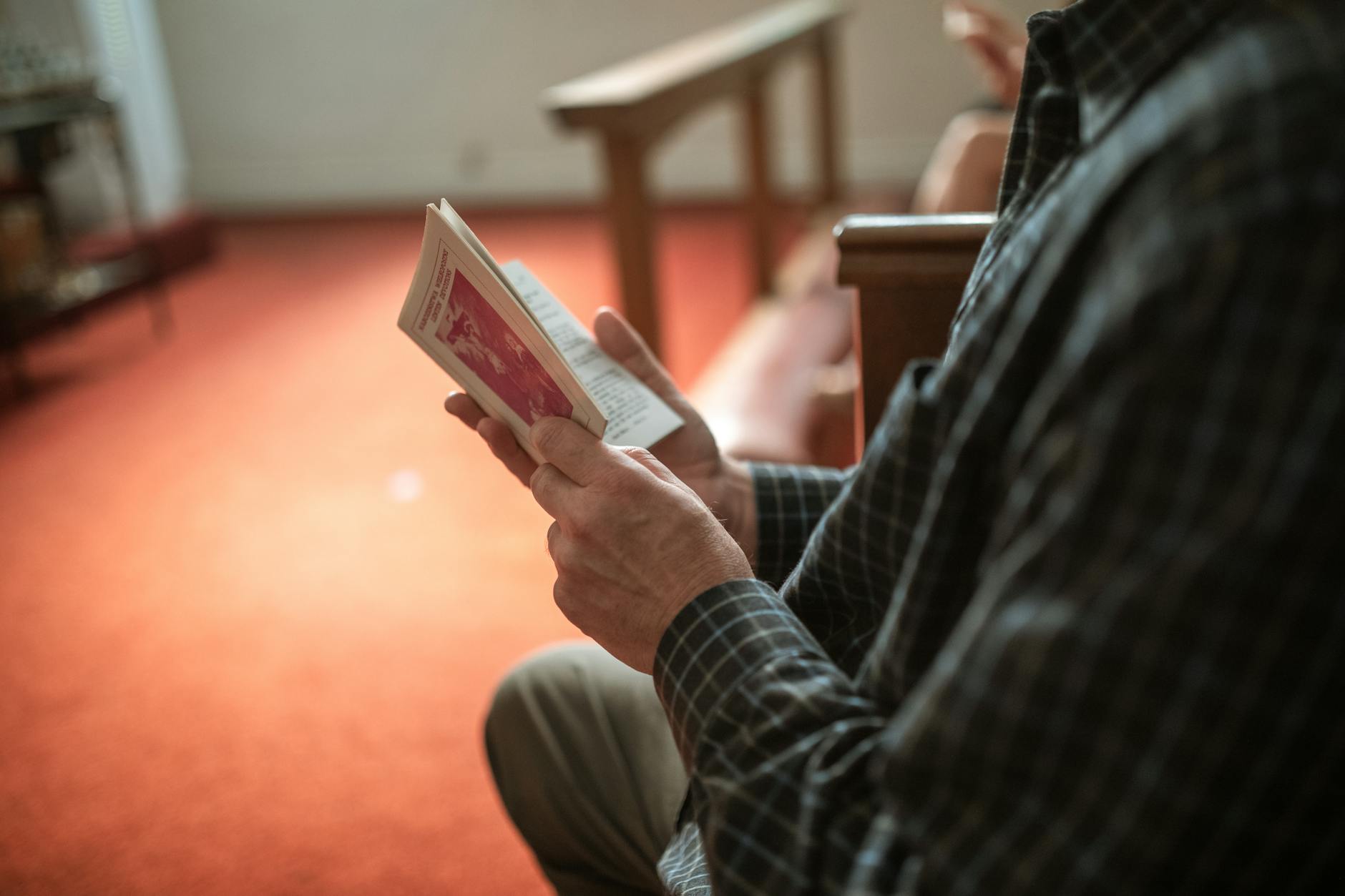Osoba czyta tekst religijny w ławce kościoła podczas nabożeństwa