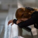 Rudowłosa kobieta pogrążona w modlitwie, oparta o ławkę w kościele