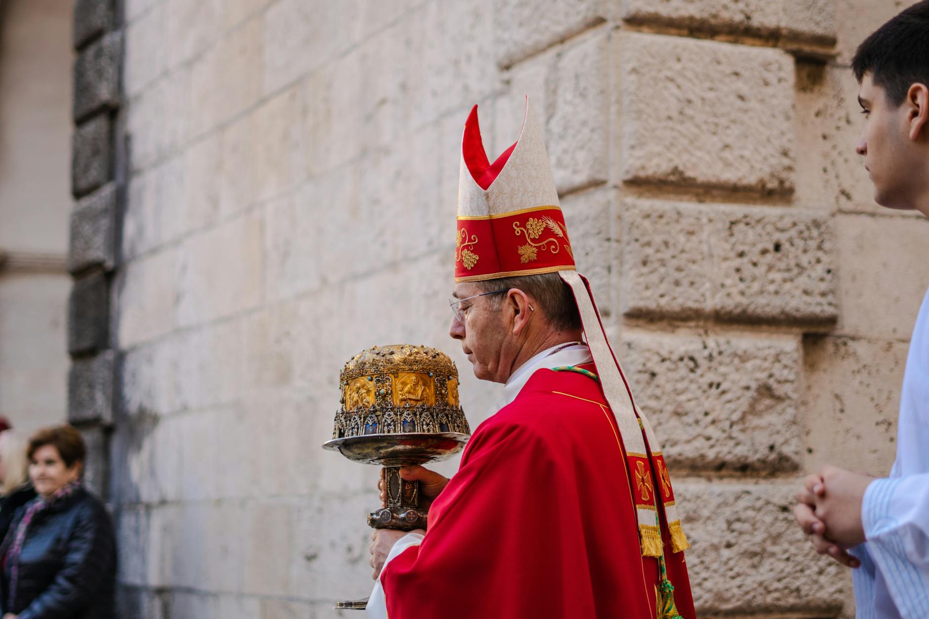 Biskup w czerwonych szatach liturgicznych z pastorałem podczas ceremonii