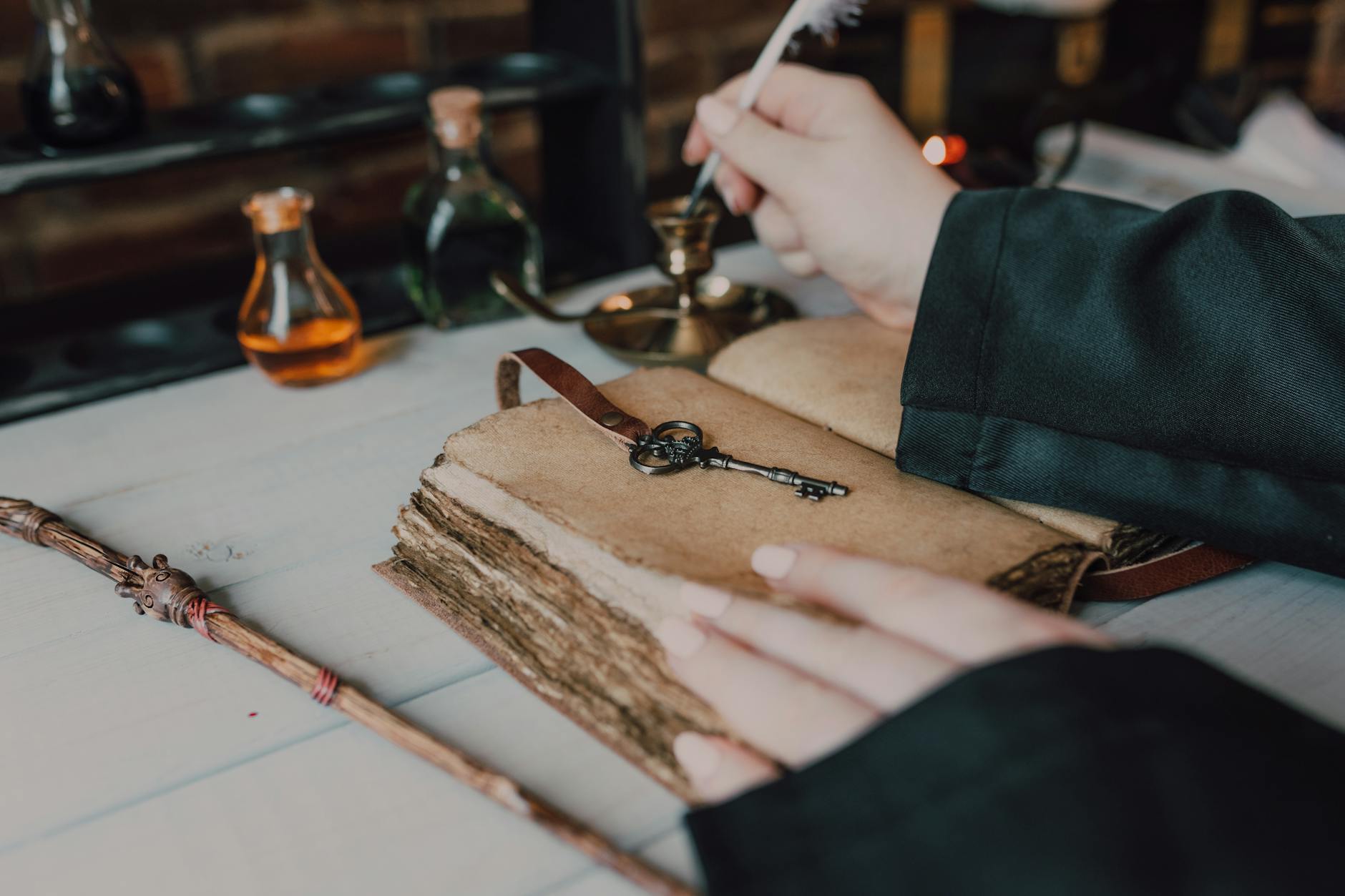 Pióro gęsie, stara księga i buteleczki z miksturami na drewnianym stole