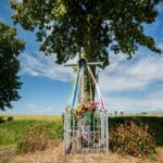 Przydrożna kapliczka z wstążkami na tle polskiej wsi i błękitnego nieba