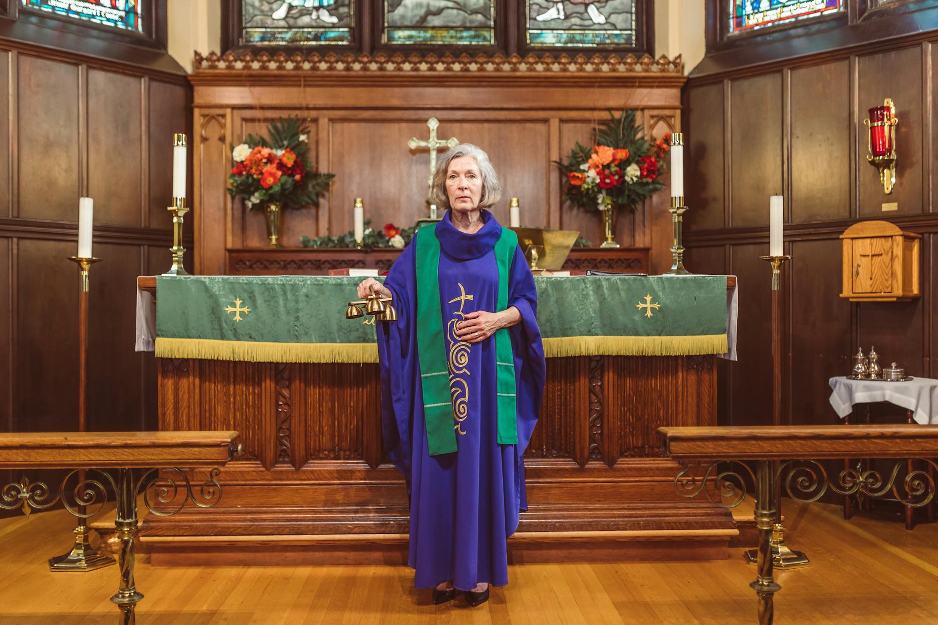 Starsza zakonnica z dzwonkiem przy ołtarzu udekorowanym kwiatami
