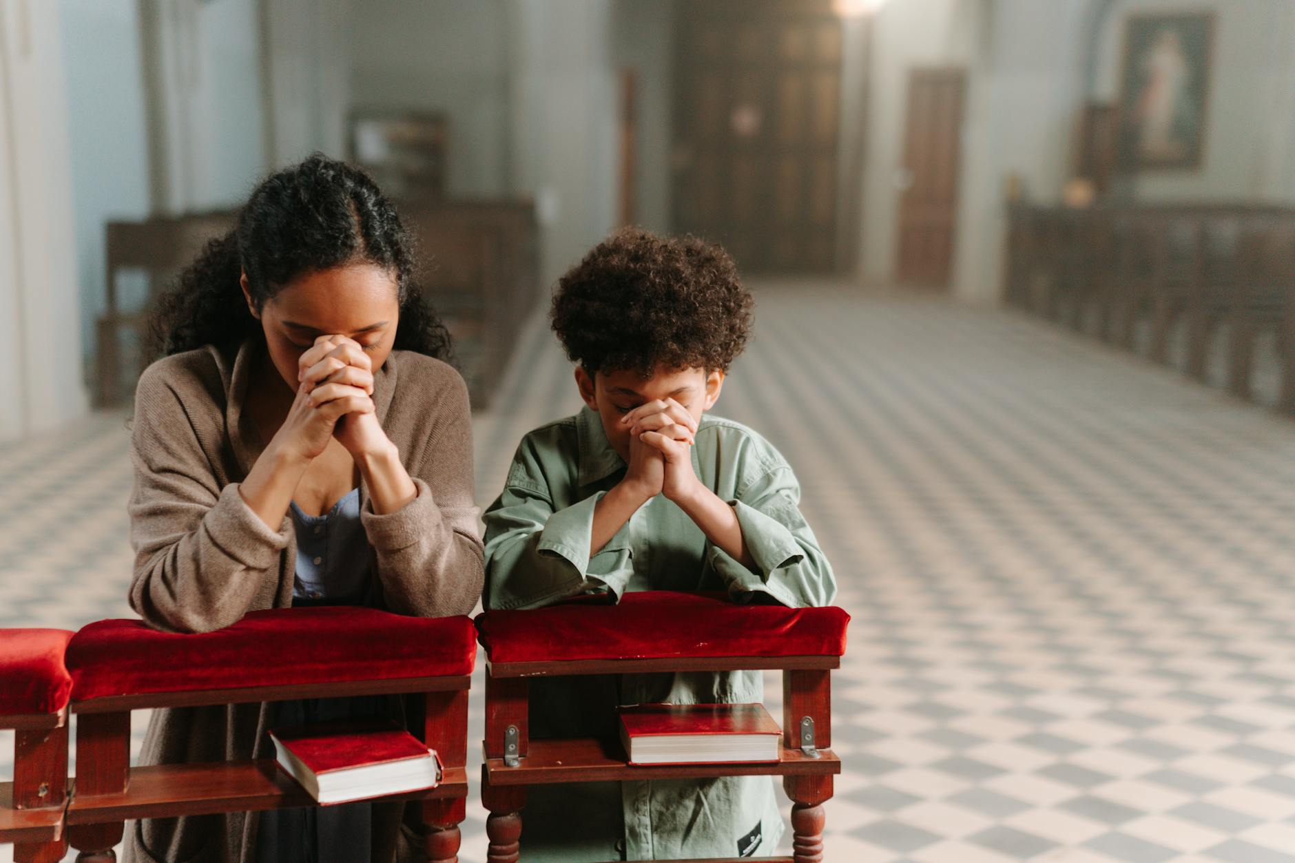 Matka i syn klęczą i modlą się razem w spokojnym kościele