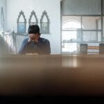 Mężczyzna pogrążony w modlitwie w jasnym, nasłonecznionym pokoju