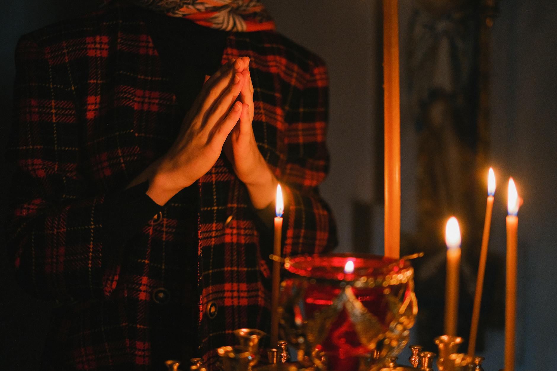 Osoba modląca się przy świecach w ciemnym kościele