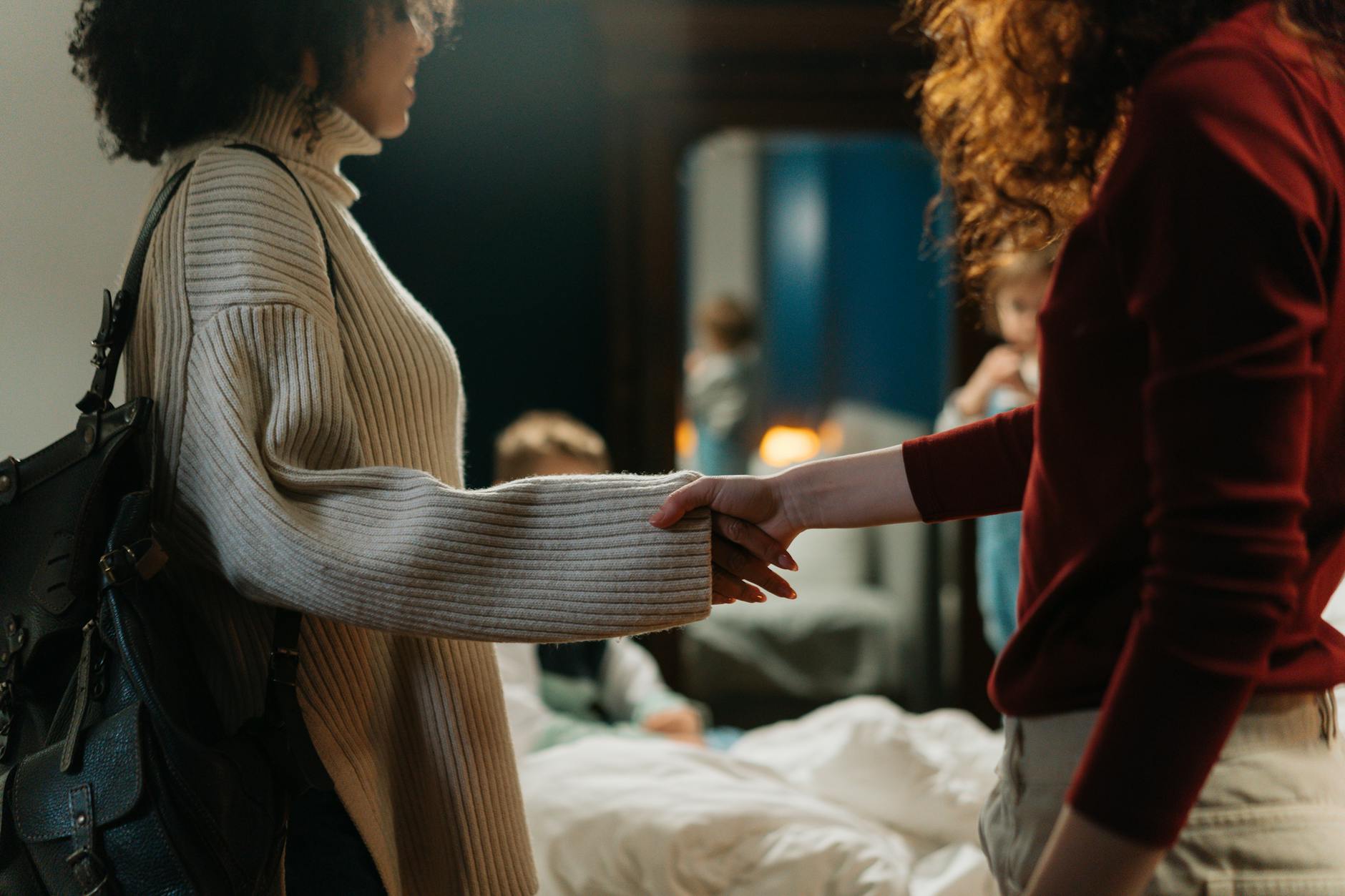 Dwie kobiety ściskają sobie dłonie w przyjaznej rozmowie indoors