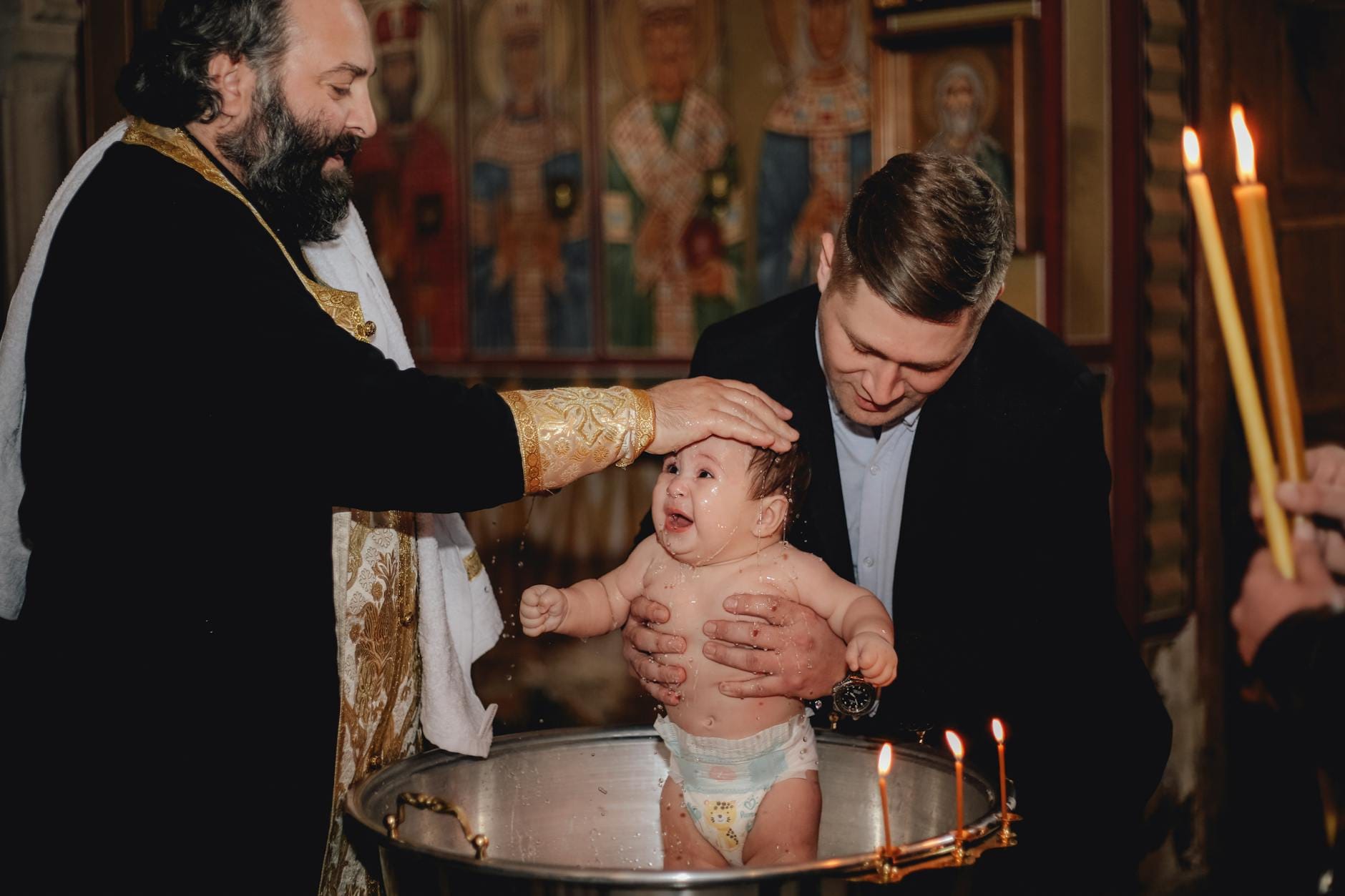 Kapłan chrzci niemowlę w kościele podczas tradycyjnego obrządku